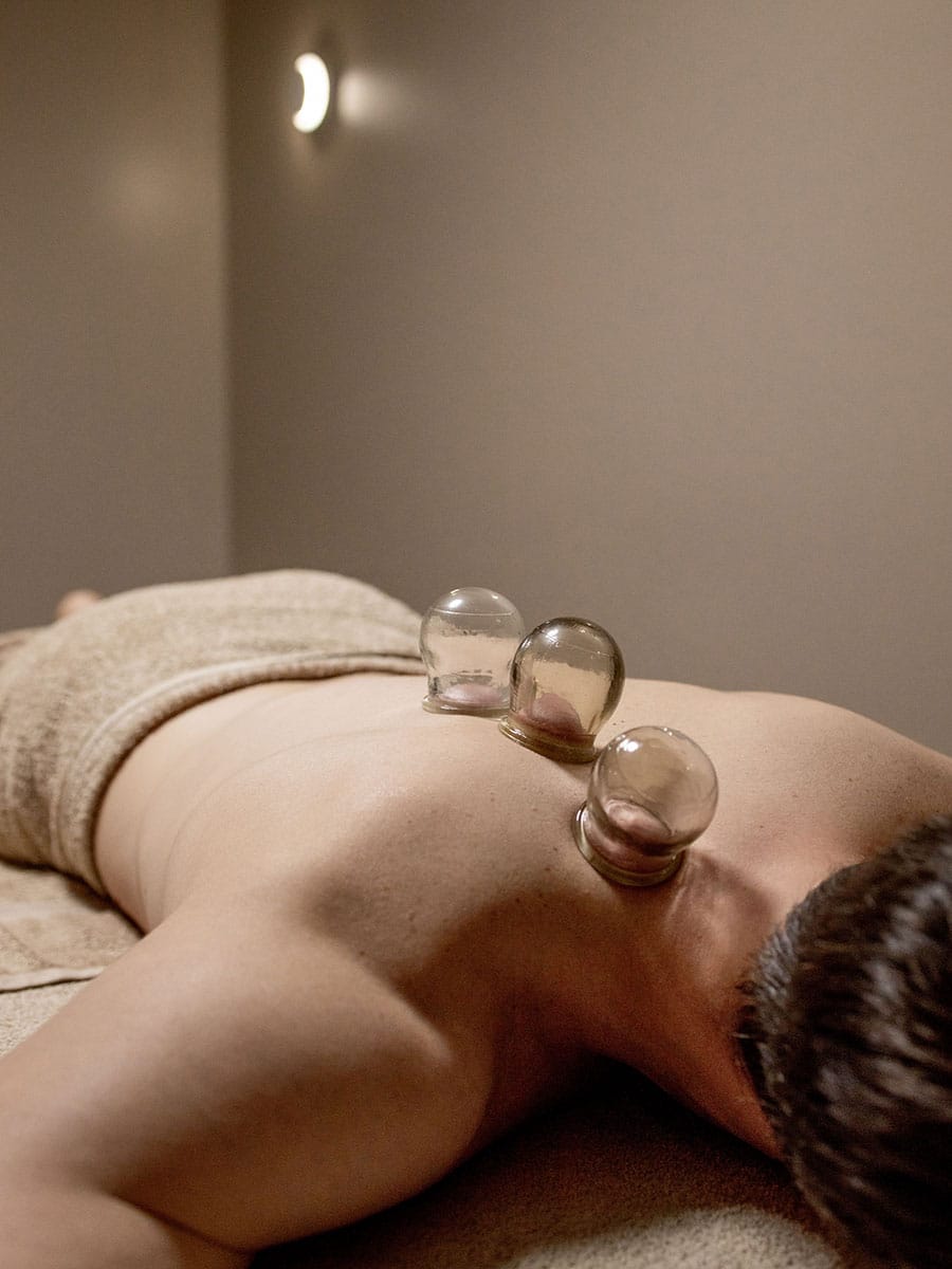 A woman with her eyes closed and a peaceful expression receiving a forehead massage from a therapist.